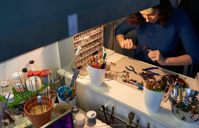 Artesana joyera utilizando pinzas para crear collares artesanales de cuentas