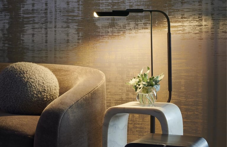 Modern living room with a sleek floor lamp, marble side table, and elegant textured gold wallpaper.