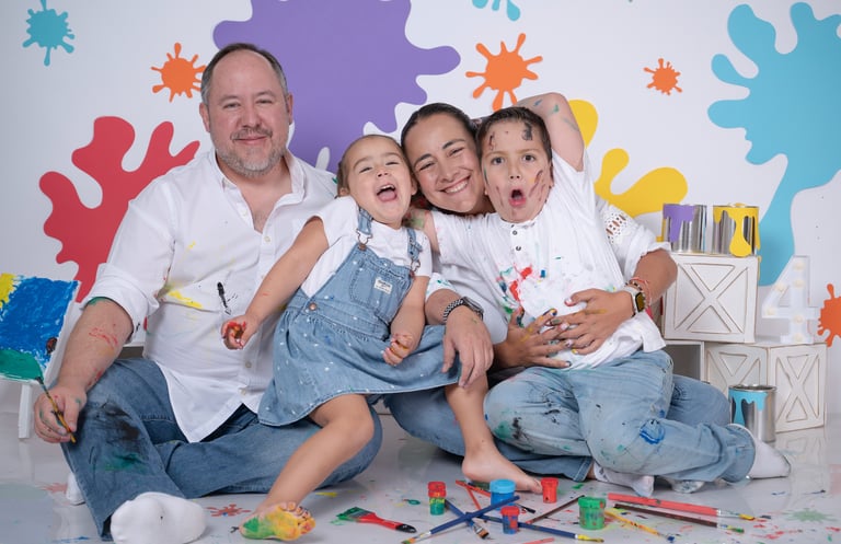 a family posing for a photo in front of a wall with paint splatters
