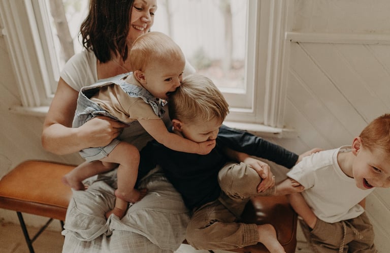 a woman holding a baby and two children