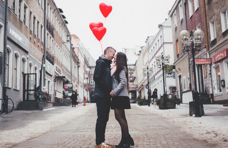 San Valentín, Una Pareja a punto de besarse en medio de la calle, con globos de corazón al fondo