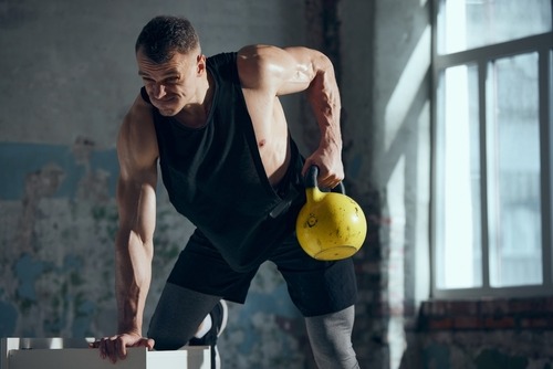 a man in a black tank using a kettlebell