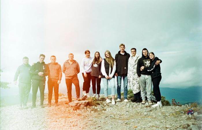 Group of young people standing together on a hill, symbolizing community and friendship.