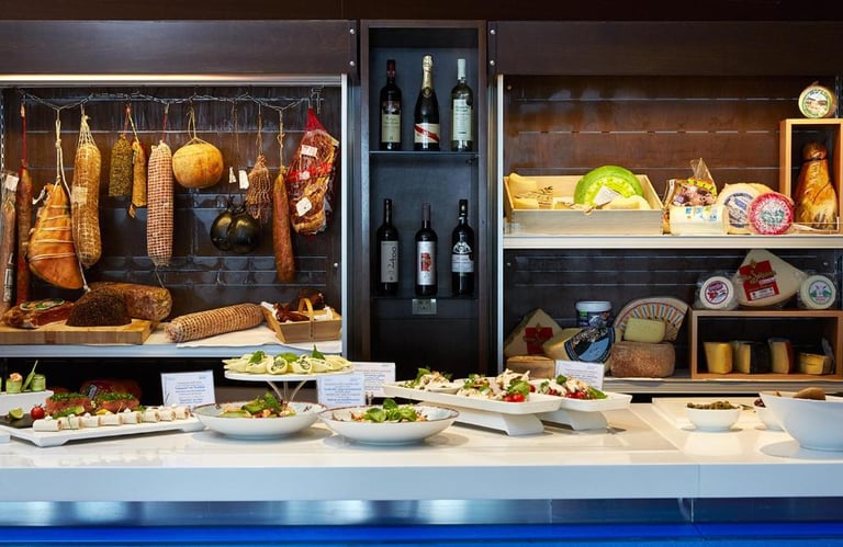 Gourmet Italian deli display featuring cured meats, artisan cheeses, wine bottles, and fresh appetizers.