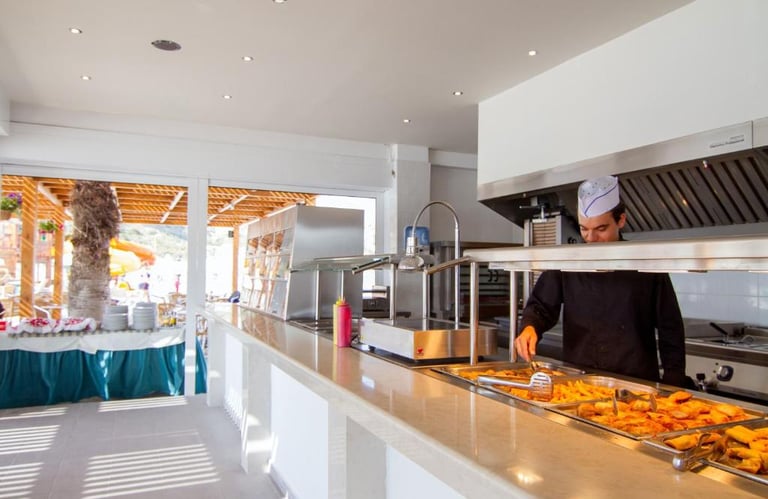 Professional chef serving hot food at a bright resort buffet station with outdoor seating.