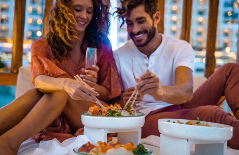 A happy couple enjoying a romantic sushi dinner with wine at a luxury outdoor restaurant.