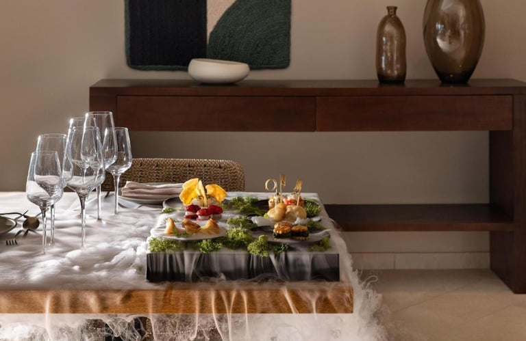 Elegant fine dining appetizers served with dry ice mist on a wooden table with wine glasses.