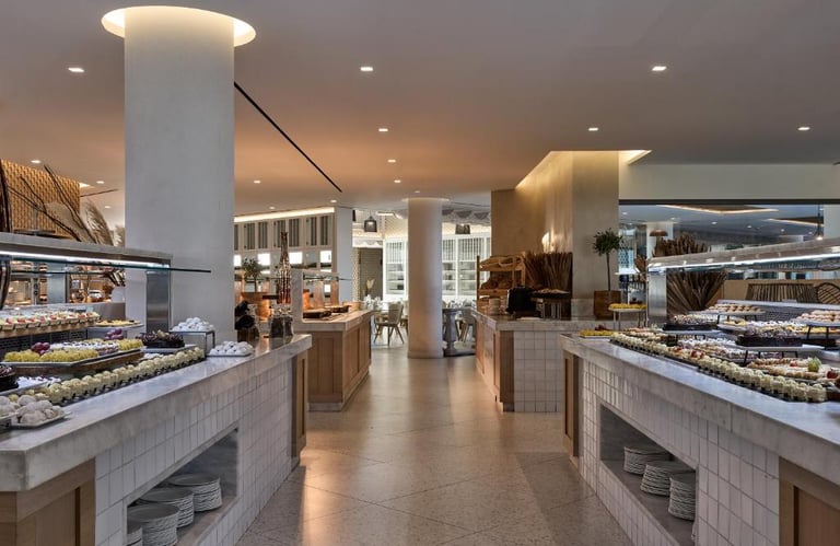 Luxury hotel buffet area featuring a variety of desserts on marble counters in a modern restaurant.
