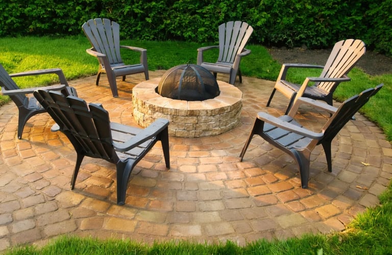 Foyer extérieur circulaire en pierre avec chaises Adirondack sur terrasse en pavés par M2 Paysage