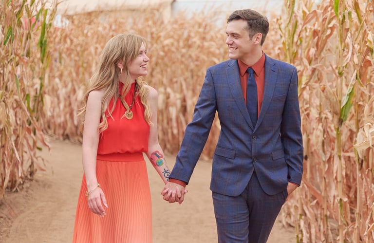 a man and woman holding hands and walking through a corn maze