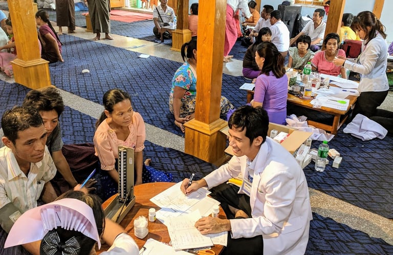 Doctor Zaw surrounded by patients sitting and counselling them in a smile