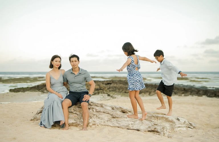 Family sharing playful moments on coastal rocks during a family photography session at The Ritz-Carlton Bali.