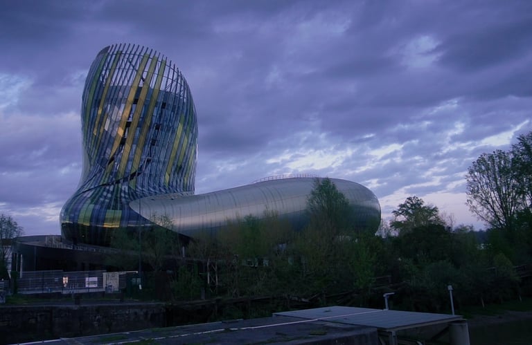 The modern architecture of La Cité du Vin wine museum in Bordeaux under a dramatic evening sky.