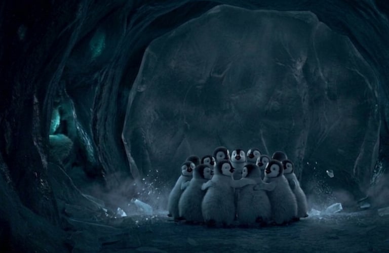 A group of fluffy baby emperor penguin chicks huddle together for warmth inside a dark ice cave.