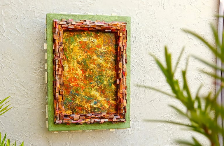 Abstraktes Bild mit Rahmen aus kleinen dunklen Holzscheiten und einem weiteren, grünen Betonrahmen