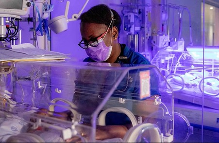 African nurse wearing mask tending baby in an ICU (Photo courtesy of the APFP)