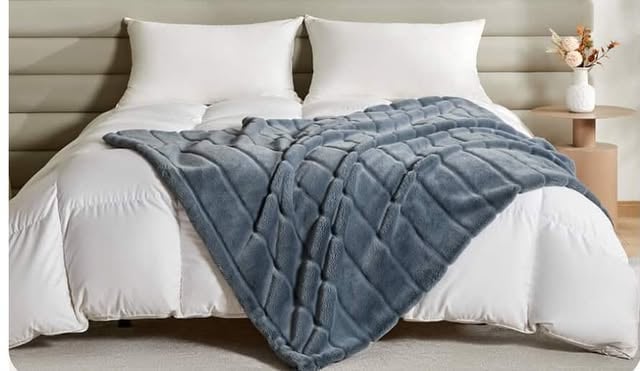 Made bed with plush weighted blanket draped over white bedding for cozy comfort