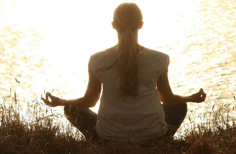 a woman sitting in a field with her hands on her knees