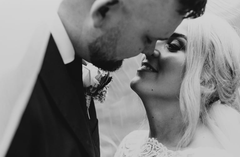 a bride and groom kissing in a black and white photo