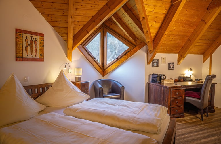 Interieurfotografie eines Hotelzimmers mit Holzdach und gemütlichem Bett