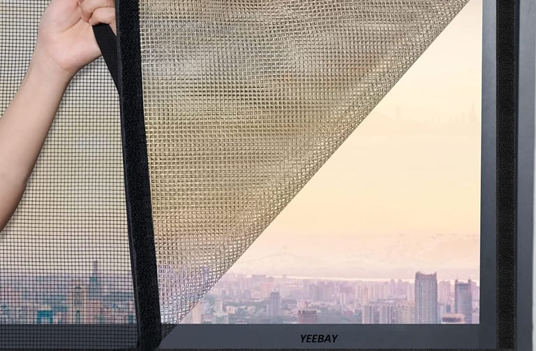 Bright room with a window fitted with a clean, white velcro mosquito net letting in sunlight.