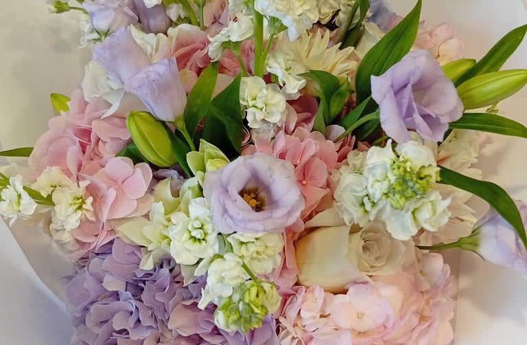 Elegant floral bouquet with pink and purple hydrangeas, lavender lisianthus, and white stocks.