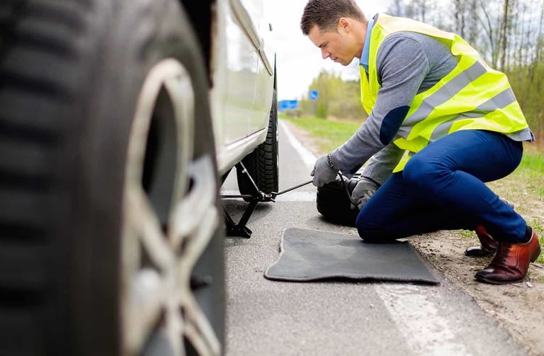 a man in a yellow vest is fixing a tire on a car