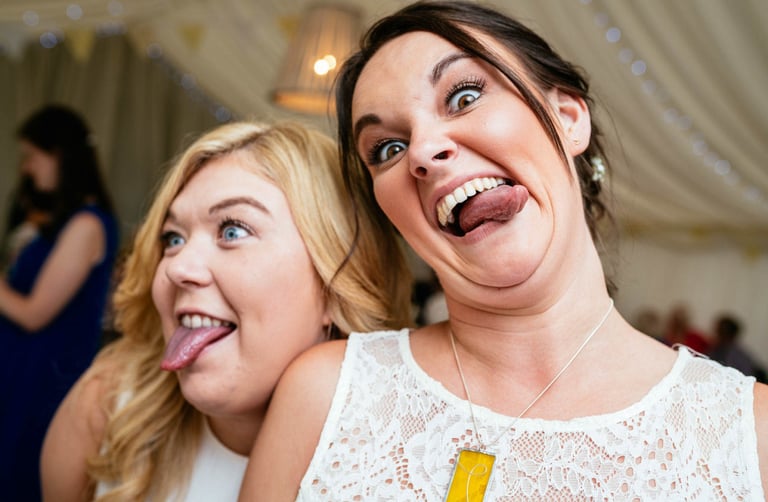 Wedding guests pulling funny faces inside marquee at a South Wales celebration, photographed by Owen Mathias