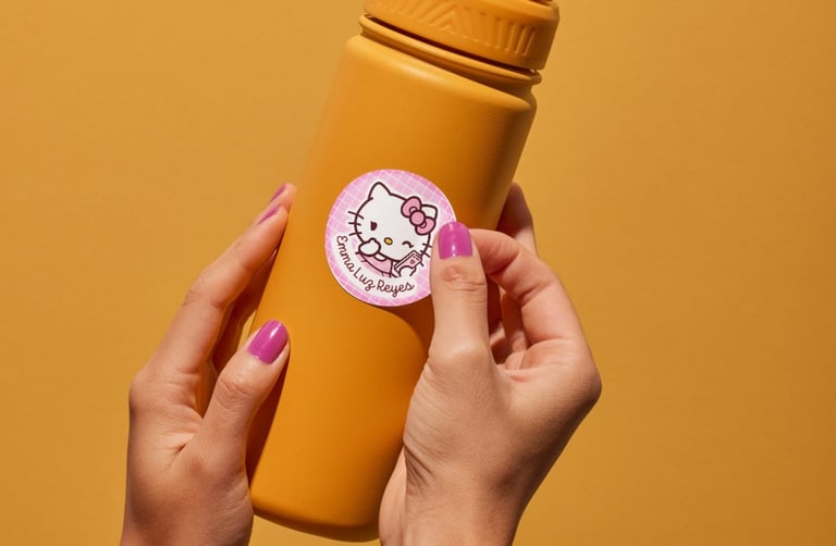 Hand applying a custom Hello Kitty sticker label to a yellow reusable water bottle.