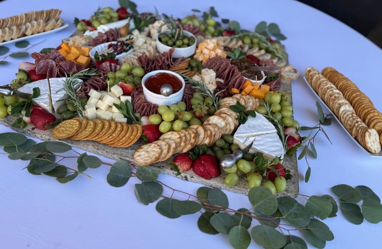 Elegant charcuterie board display with meats, cheeses, fruit, crackers, and fresh garnish