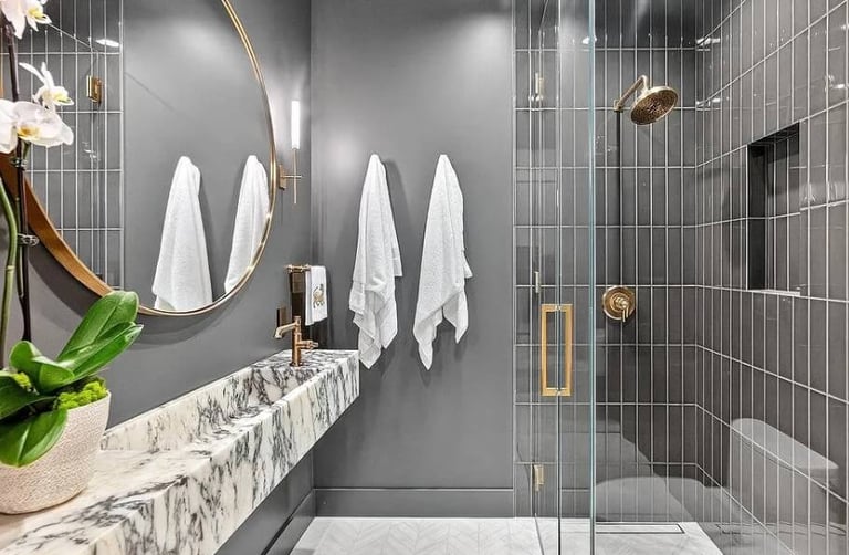 Bathroom remodel with a wall-mounted sink, round mirror, and glass-enclosed shower.