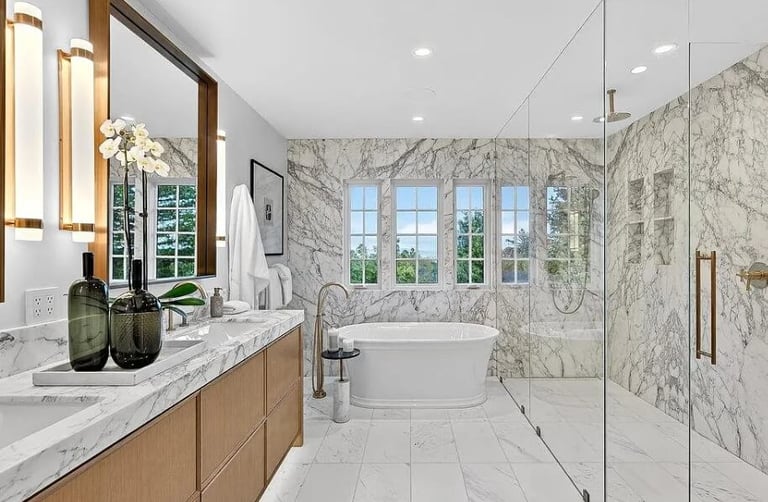 Bathroom remodel with a freestanding bathtub, marble tile, and glass-enclosed shower.
