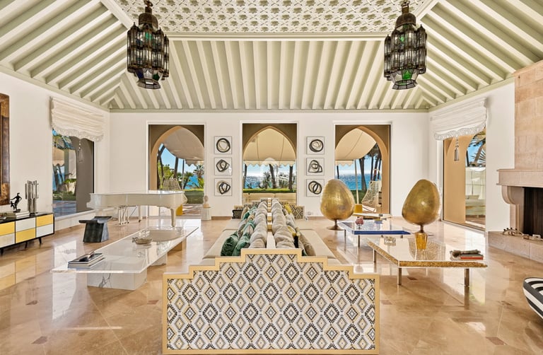 Elegant living room with grand piano, fireplace and arched ocean views