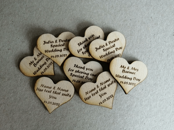 Personalized wooden heart wedding favors with custom engraved names and dates for guest table decor.