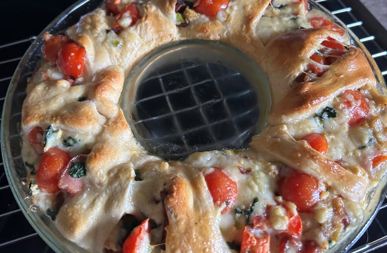 Ring of Goodness dish just out of oven. Breaded top with tomatoes, cheese and veggies sticking out the top.