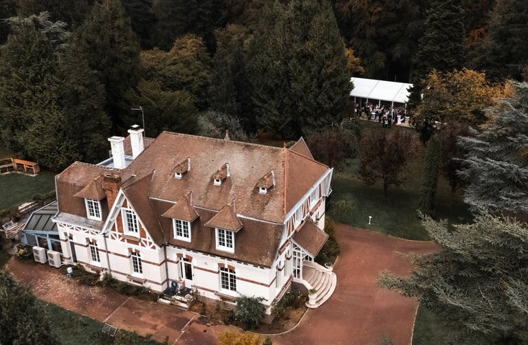 Une maison normande vue du ciel dans un parc boisé