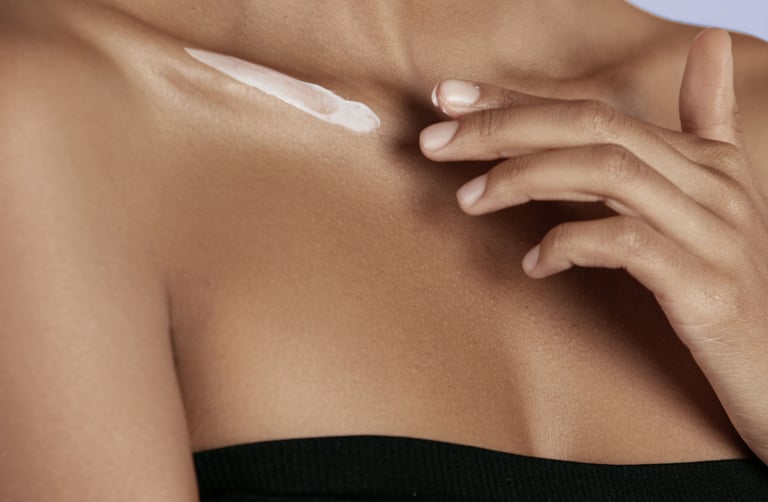 black woman applying shea butter to her shoulder