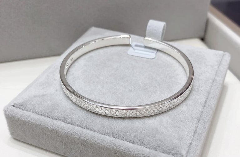 Minimalist semijoias in gold tones placed beside a small green plant for a fresh look.