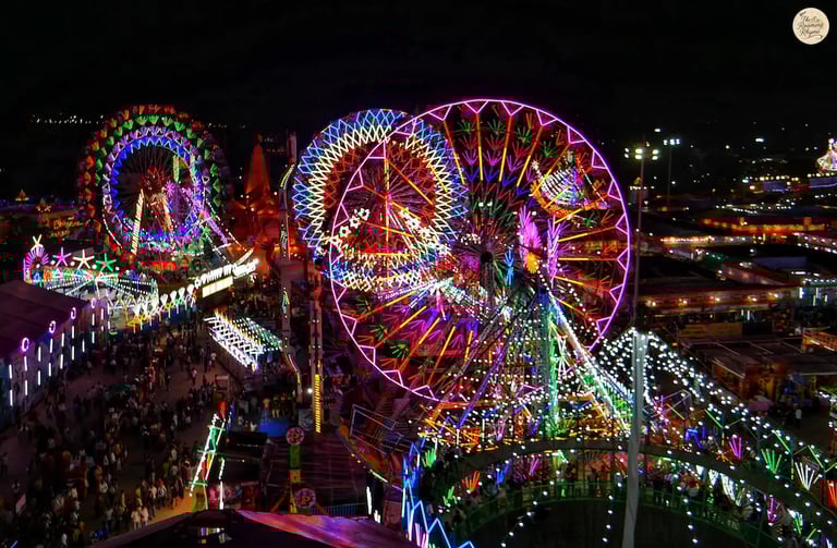 Night aerial view of Kota Dussehra Mela with glowing giant wheels, dazzling rides, and illuminated stalls.