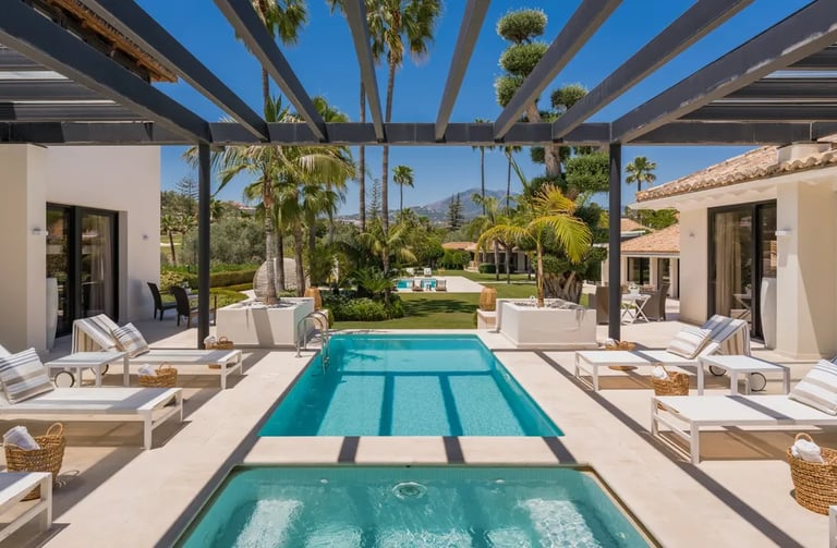 Guest heated pool surrounded by terraces and palm gardens at Villa El Olivo, Marbella