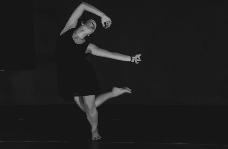 a woman in a black dress is dancing in a black and white photo