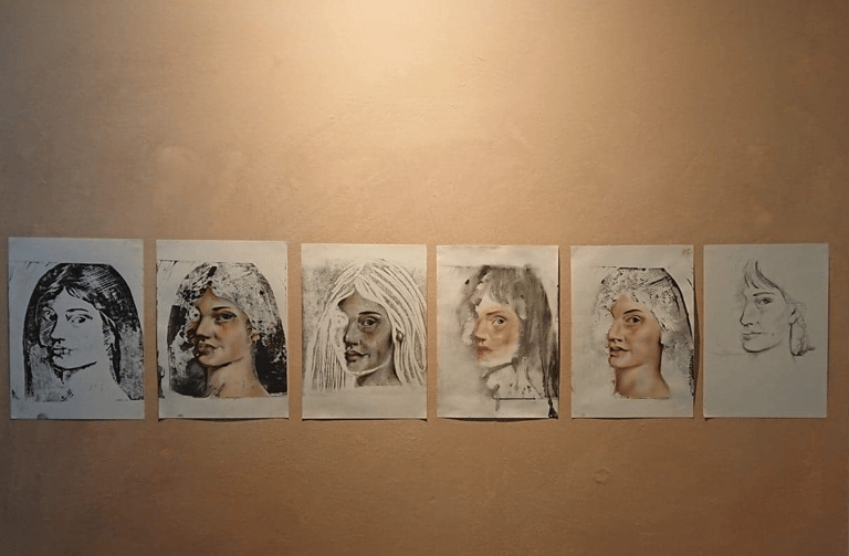 6 print and mixed media portraits of a lady on a painted rectangle section on wall.
