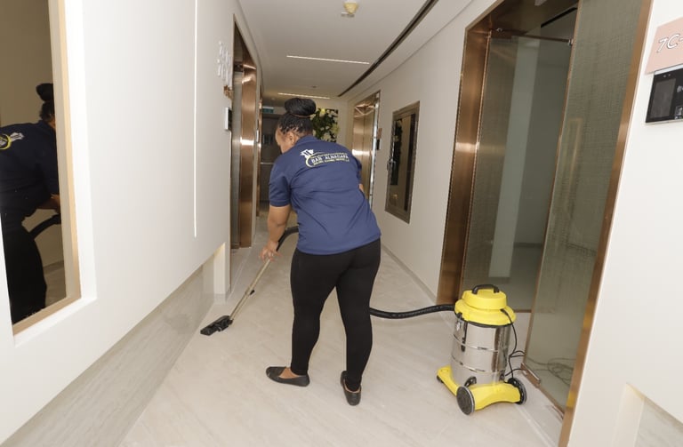 a cleaner in a blue shirt is cleaning a hallway