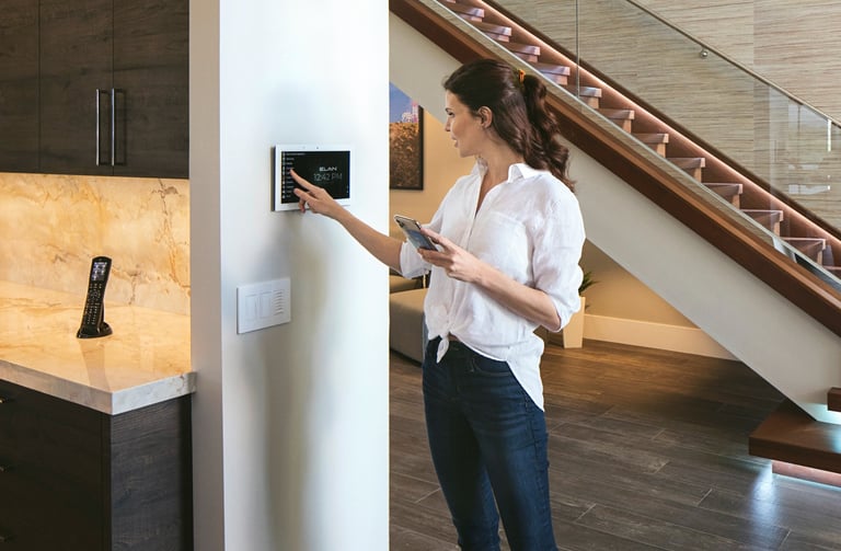 Client using a wall-mounted Nice ELAN touch panel for smart home lighting control.