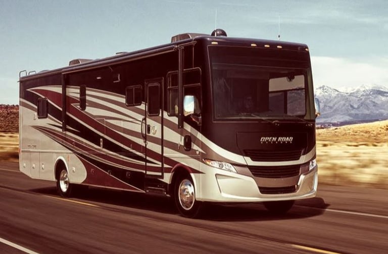 A Tiffin Allegro Open Road luxury motorhome driving on a highway with mountains in the background.