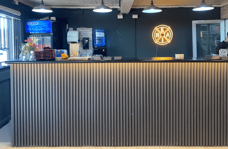 Diseño de barra de sushi listonada con iluminación técnica por Atípico Studio en Santiago.