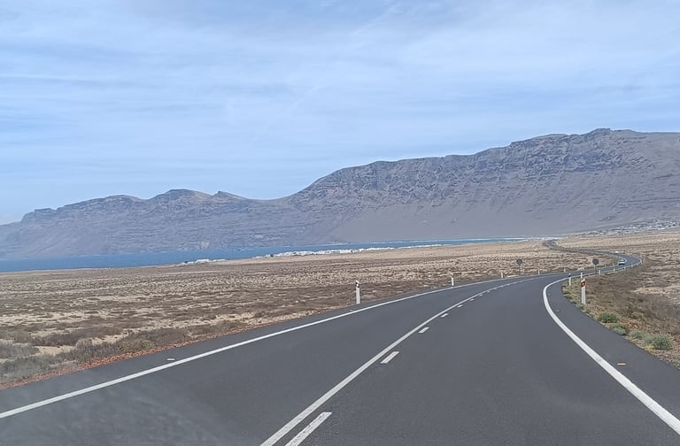 a car driving down a road with mountains in the background