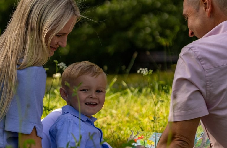Familienshooting Coburg: Entspannte Familienzeit, Eltern mit Sohn sitzen auf einer Wiese.