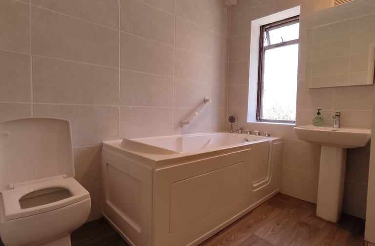 Refurbished bathroom walk-in bath installed for elderly accessibility 
