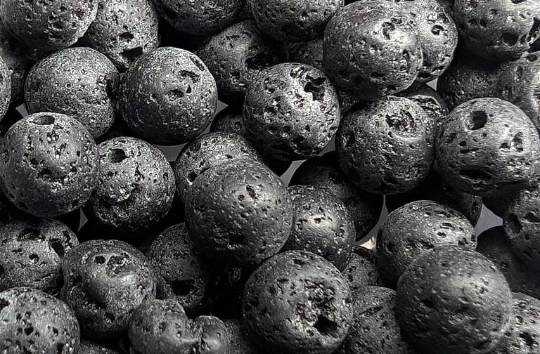 Perles en pierre de lave noire, à la texture poreuse et rugueuse, offrant un aspect brut et naturel